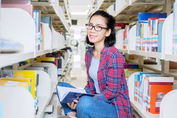 女大学生坐在图书馆过道上 对着相机微笑 — 图库照片