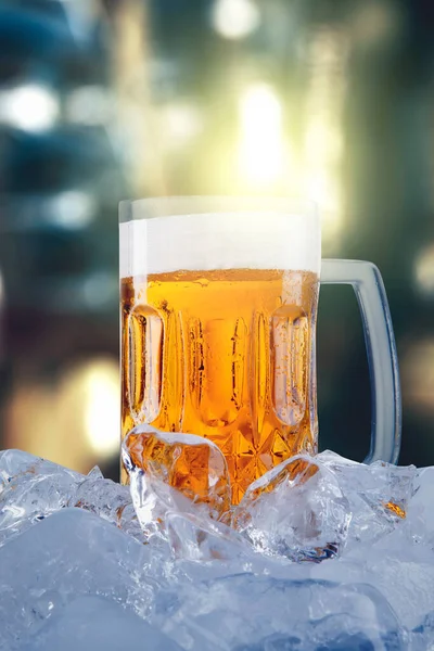 在有泡沫和冷冰冰立方体的大玻璃杯中 在灯光模糊的背景下 近距离饮用新鲜啤酒 — 图库照片