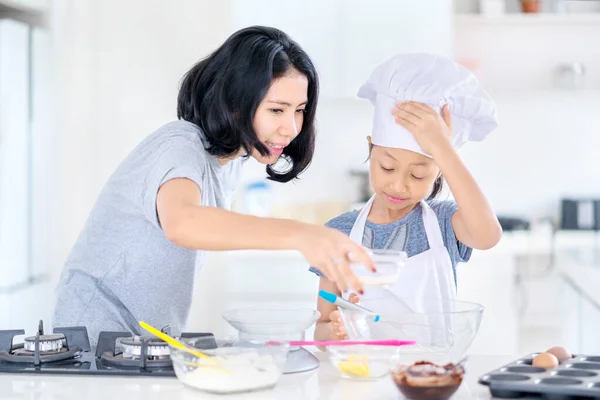 台所で娘と一緒に調理しながら ボウルに小麦粉を注ぐのを助ける若い女性 家で撃たれた — ストック写真