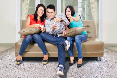 Bir grup neşeli insan kanepede otururken oturma odasında oyun oynuyorlar. Evde vuruldu.