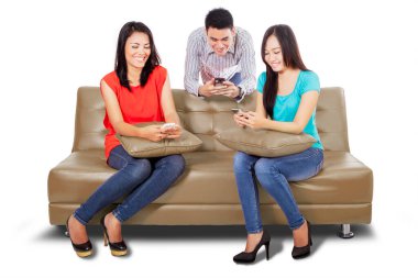 Bir grup mutlu insan koltukta otururken internete girmek için cep telefonlarını kullanıyor. Beyaz arkaplanda izole