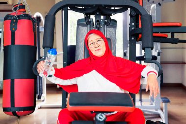 Spor salonundaki antrenmandan sonra elinde içki şişesiyle beden eğitimi dersinde oturan son sınıf öğrencisi kadın.