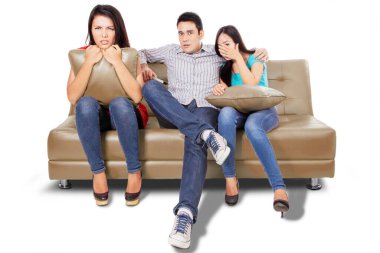 Kanepede birlikte otururken TV 'de korku filmi izleyen üç genç insan. Beyaz arkaplanda izole