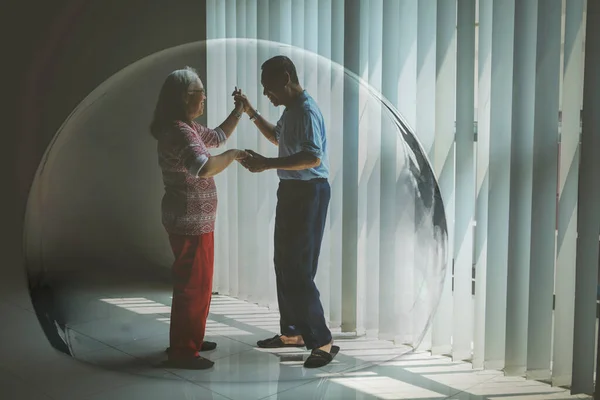 高齢者のカップルは家の窓の近くで一緒に踊っている間 保護バブルで幸せな気分 — ストック写真