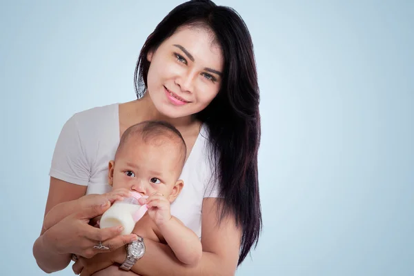 Hermosa Madre Sonriendo Cámara Mientras Alimenta Bebé Desde Biberón Sentado —  Fotos de Stock