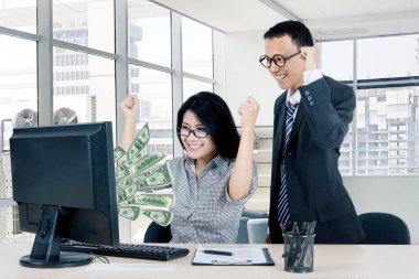 Ofisteki bilgisayarlarından paralarına bakarken iki mutlu işçi başarılarını kutluyor.