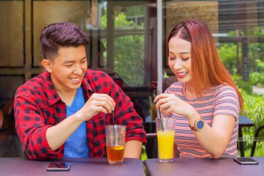 Genç ve mutlu bir çift, kafeteryada oturup içki içerken sohbet ediyor.