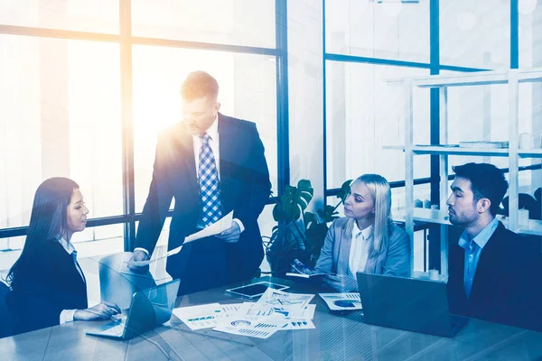 Male manager giving a paper of report business plan while meeting in the office with sunlight background