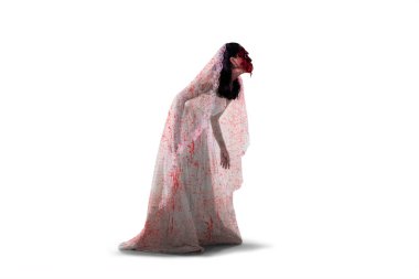 Halloween horror concept. Side view of horrible female ghost wearing bloody bride gown and walking in the studio clipart