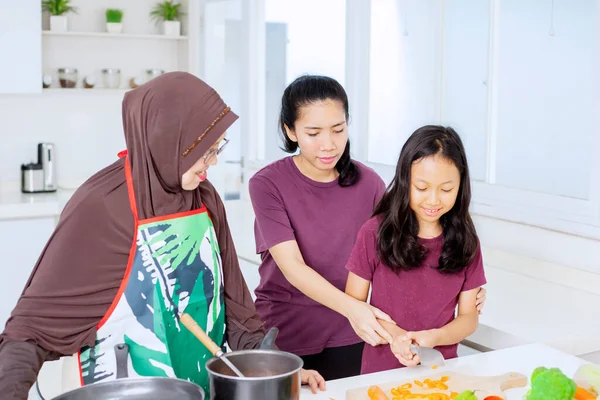 小さな女の子は台所で一緒に調理しながら 彼女の母親と祖母と野菜をスライスすることを学びます — ストック写真