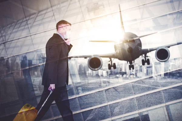 Double exposure of businessman wearing face mask while carrying a luggage and walking with airplane take off background