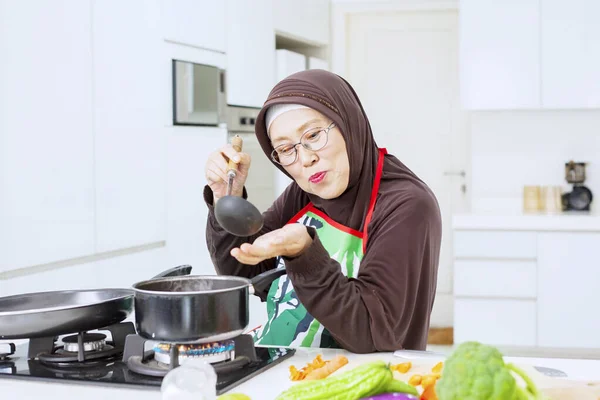 Yaşlı Müslüman Kadın Mutfakta Dururken Tencerede Çorba Tadıyor — Stok fotoğraf