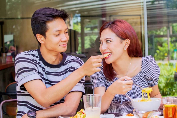 テーブルの上においしい食べ物とレストランで一緒に昼食を取りながら ロマンチックな若い男は彼のガールフレンドを養う — ストック写真