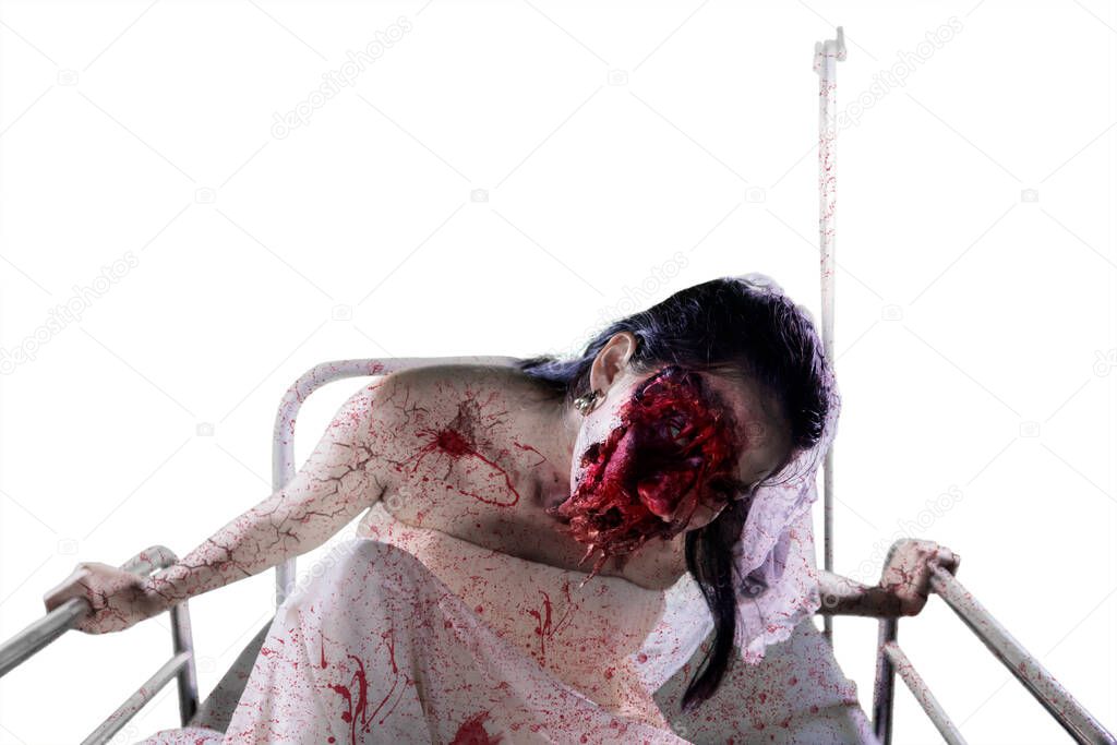 Halloween horror concept. Scary female bride with wounded face sitting on the hospital bed, isolated on white background