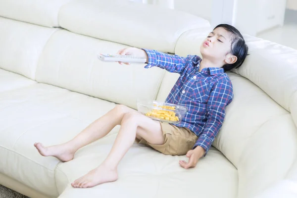 Imagem Menino Parece Entediado Enquanto Segurando Controle Remoto Televisão Sentado — Fotografia de Stock