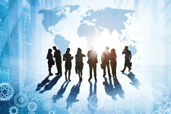 Silhouette of business people working in busy office while standing with double exposure of world map and cogwheel background