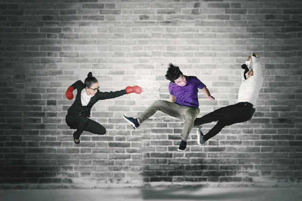 Junge Geschäftsfrau Trägt Boxhandschuhe Während Sie Ihre Rivalen Mit Backsteinmauern — Stockfoto