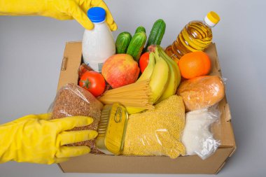 Çeşitli yiyeceklerle birlikte bağış kutusu. İçinde yağ, konserve yiyecek, mısır gevreği ve makarna olan karton kutuyu aç..
