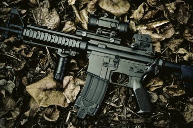 Silah ve askeri teçhizat için ordu, orman arka plan taarruz tüfeği topu (M4a1) kuru yaprakları.
