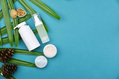 Kozmetik şişe kapları ile yeşil bitki yaprakları, marka mock-up, doğal organik güzellik ürün kavramı için boş etiket paketi.