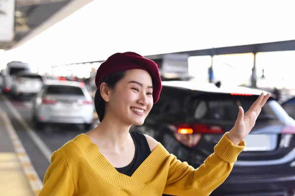 Азіатські жінки називають автомобіль таксі в аеропорту, Веселі дівчата посміхаються і розмахуючи рукою, Привіт жест. — стокове фото