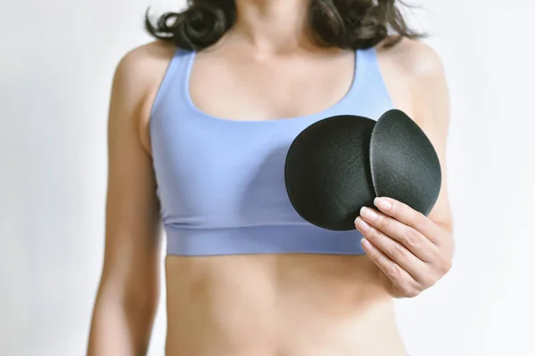Upsize your breast, Woman in sportwear showing a bra insert extra pad,  Thick sponge for breast enhancer, Asian girls have small breasts. Stock  Photo