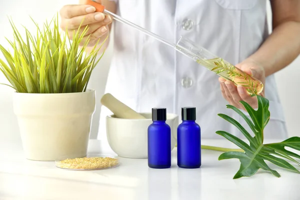 Natural skincare cosmetics research and development concept, Doctor formulating new beauty products from organic natural plants, Pharmacist mixing extract essence substance in tube, Blank container.