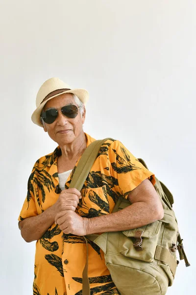 Asiatischer älterer Herr in buntem Hemd mit Rucksack, Senioren freuen sich auf eine Urlaubsreise, glücklicher aktiver Ruhestand. — Stockfoto