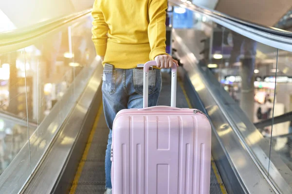 Reiziger dragen grote koffer op roltrap loopbrug op de terminal van de luchthaven, passagier wandelen met bagage naar vertrek incheckbalie, toerist aankomen op bestemming, reis concept. — Stockfoto