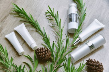 Yeşil bitkisel yapraklarla paketlenmiş kozmetik şişe kapları, organik markalaştırma için boş etiket, doğal cilt bakımı ürün konsepti.