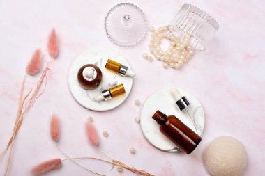 Pembe mermer arka planda kozmetik şişe kapları, markalaştırma için boş etiket paketi, doğal organik güzellik ürünü konsepti, saflaştırılmış cilt bakımı ve gelişimi.