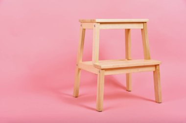 Minimum iç mekan tarzı, pastel pembe arka planda ahşap sandalye ayrıntıları, minimalizm mobilyaları.