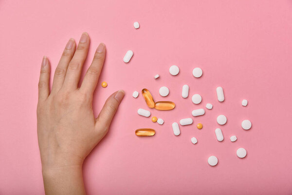 Assorted pharmaceutical medicine, Hand taking too much medication pills, Overdiagnosis drugs cause bad health.