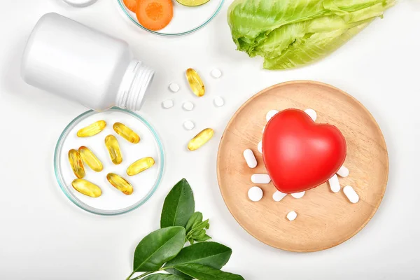 Vitamin nutrition pills and heart model, Natural medicine supplement from organic fresh fruit and vegetable, Healthy beauty food diet.