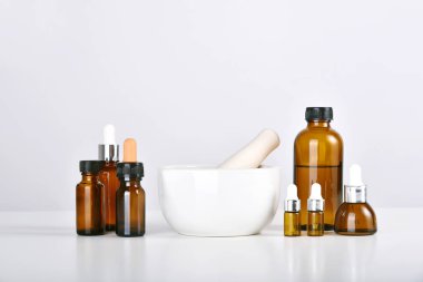 İlaç şişeleri ve temiz sıvı çözeltisi, uyuşturucu araştırma ve geliştirme konseptiyle havan ve bilimsel laboratuvar vitrinleri.