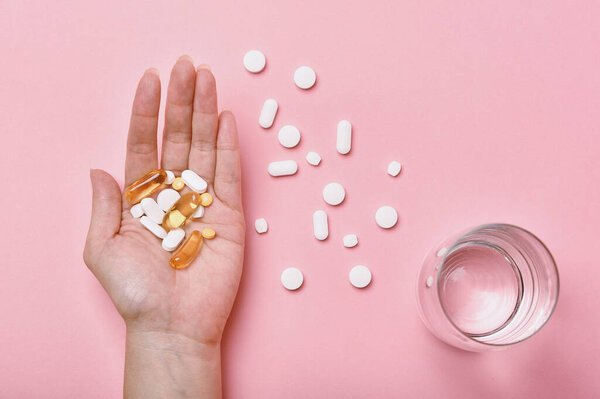 Assorted pharmaceutical medicine, Hand taking too much medication pills, Overdiagnosis drugs cause bad health.