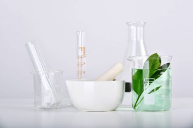 Doğal organik özüt ve yeşil bitkisel yapraklar, laboratuarda bilimsel cam eşyalar..
