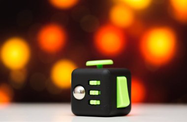 Küp antis stres oyuncak kıpır. Parmak detayını oynamak oyuncak relax için kullanılan. Gadget'ı renkli bokeh arka plan üzerine yerleştirilen.