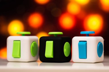 Küp antis stres oyuncak kıpır. Parmak detayını oynamak oyuncak relax için kullanılan. Gadget'ı renkli bokeh arka plan üzerine yerleştirilen.