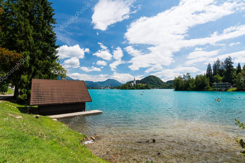 Bled lake, Slovenia. Pure blue water and swimming peoples in the lake, near church on the island on middle of the lake.