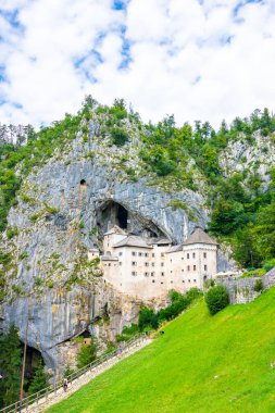 Predjama Kalesi, Slovenya. Postojna yakınındaki Predjama Kalesi'nin doğal görünümü mağara ağzını. Anciend mimari kayaya inşaatı. Eski Ortaçağ Kalesi, güneşli yaz gün
