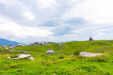 Slovenya velika planina (büyük Yaylası), tarım mera arazi şehir Sloven Alpleri'nde Kamnik yakınlarında. Yeşil arazi herdsmen tarafından kullanılan ahşap evler. Dağ köyü ile büyük mera Yaylası