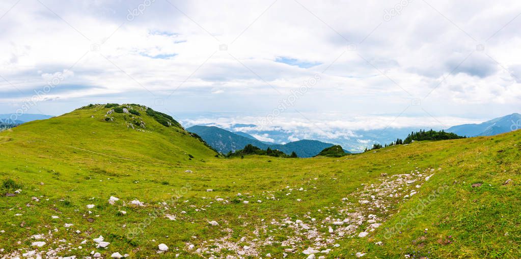 Panoramatic view to Slovenia Alps near city Kamnik. Big plateau with pasture and wooden houses. Landscape with green grass and clouds above the hill