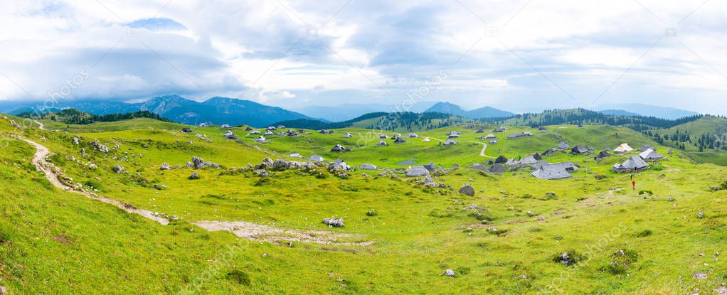 Slovenia velika planina (big plateau), agriculture pasture land near city Kamnik in Slovenian Alps. Wooden houses on green land used by herdsmen. Mountain village with big pasture plateau