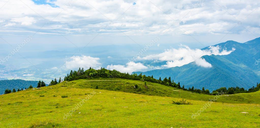 Slovenia mountains near the Kamnik city on Velika Planina pasture land. View of mountains with white clouds and blue sky, mist in the hill. Beautiful and tranquil nature, fresh grass.