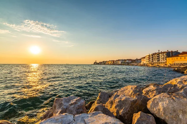 Şehirde Piran, Slovenya Adriyatik Denizi üzerinde gün batımı. Eski antik ve mediaveal şehir, kıyı ve liman görünümden. Ön plan, güzel bulutlar gökyüzü üzerinde şehir üzerinde romantik günbatımı eski taş