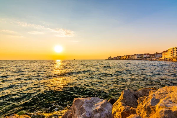 Şehirde Piran, Slovenya Adriyatik Denizi üzerinde gün batımı. Eski antik ve mediaveal şehir, kıyı ve liman görünümden. Ön plan, güzel bulutlar gökyüzü üzerinde şehir üzerinde romantik günbatımı eski taş