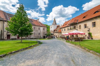 Krivoklat, Çek Cumhuriyeti - 12.6.2020: Krivoklat kalesindeki avlu manzarası. Turistler çimde ya da bankta dinleniyor. Kale kulesinin manzarası. Yaz havası, bulutlu güneşli bir gün..