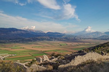 Gün batımında vadi. Renkli mavi bulutlu gökyüzü ve dağların arka planına karşı yetiştirilmiş alanlar. Doğa ve seyahat. Arnavutluk, Vlora Ilçesi, Saranda yakınında