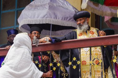 Addis Ababa, Etiyopya - Ocak 02, 2014: Holytide. Bakan tören cübbesi giyiyor. Cemaat üyesi haç öpüyor.
